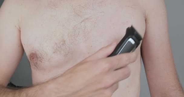 若い男は自分の世話をし 電気機械で胸を剃る 男性の美しさ 高品質4K映像 — ストック動画