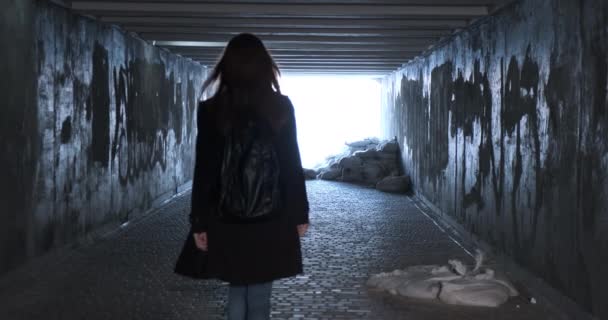 シルエットの女性が地下の通路を歩いていると 光に向かって爆弾の避難所に変わりました リアビュー みすぼらしいトンネル サンドバッグ ウクライナでの戦争 高品質4K映像 — ストック動画