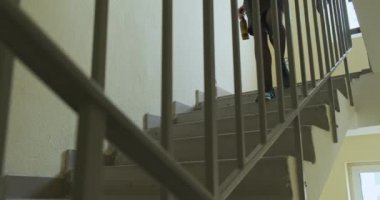 Elbiseli, sarhoş bir kadın elinde bir şişe birayla merdivenlerden iniyor. Parmaklıklardan yan görüntü. Eğlence anlayışı, yalnızlık, alkolizm, partiden sonra. Yüksek kalite 4k görüntü