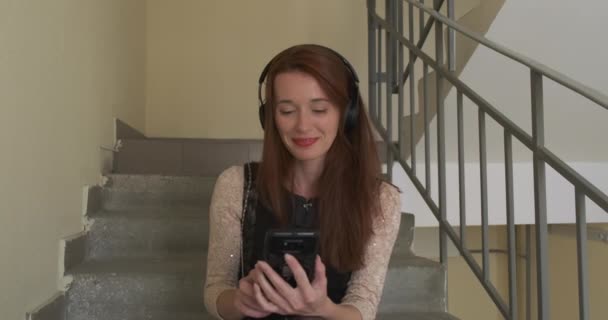 Καυκάσια Νεαρή Γυναίκα Ακούει Μουσική Ακουστικά Και Κοιτάζει Την Οθόνη — Αρχείο Βίντεο