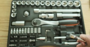 Oto tamircisi metal bir uzantıyı küçük bir anahtara bağlıyor, biraz ekliyor. Anahtarın çalışmasının gösterimi, arka planda bir takım araçlar, yakın plan, üst görünüm. Yüksek kalite 4k görüntü