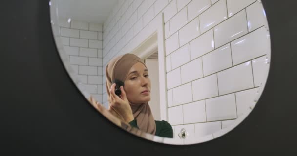 Młoda Kobieta Hidżabie Nakłada Makijaż Pędzlem Portret Łazienka Odbicie Lustrze — Wideo stockowe