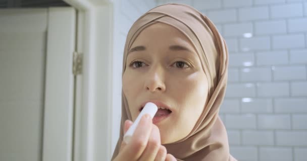 히잡의 암컷은 립스틱을 입술에 발랐습니다 클로즈업 무슬림의 전면시야 여성의아름다움 자기보살핌 — 비디오