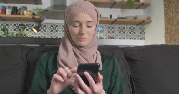 Donna Musulmana Hijab Utilizzando Smartphone Mentre Seduto Sul Divano Soggiorno — Video Stock