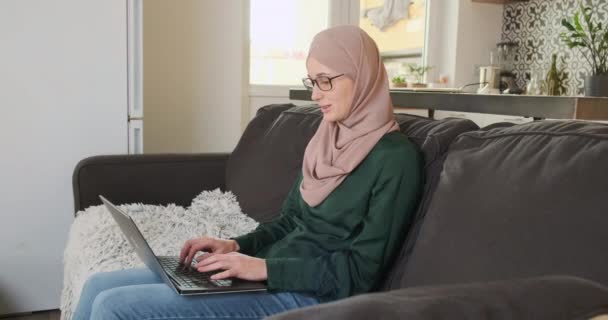 Vacker Ung Kvinna Hijab Arbetar Laptop Medan Sitter Soffan Hemma — Stockvideo