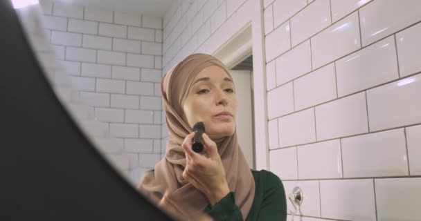 鏡の中にイスラム教徒の女性の反射 ヒジャーブの幸せな女の子はブラシで化粧を適用します 現代の女性 独立性 女性の美しさの概念 高品質4K映像 — ストック動画