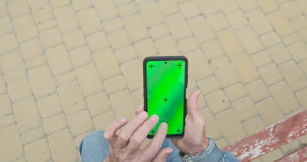 認識できない高齢者の手はスマートフォンを使用します 緑の画面 スワイプ タッチ 上のビュー ベンチ 舗装スラブ 高品質の写真 — ストック写真