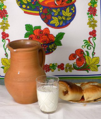 Bir bardak süt, seramik bir sürahi, masanın üzerinde yuvarlanıyor. Kahvaltı..