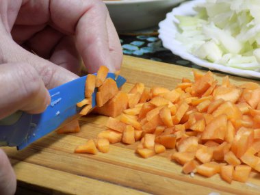 Sebzeli yemek pişirmek için mutfakta bıçakla havuç kesmek.