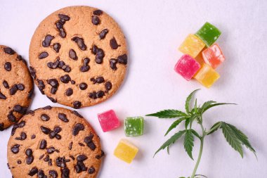 Esrar özlü Amerikan kurabiyeleri. CBD yağlı tatlılar. Beyaz arka planda marihuana yaprakları. Üst manzara, düz uzanma.