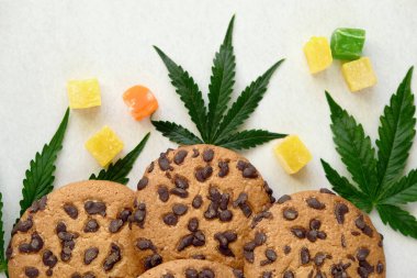 Esrar özlü Amerikan kurabiyeleri. CBD yağlı tatlılar. Beyaz arka planda marihuana yaprakları. Üst manzara, düz uzanma.