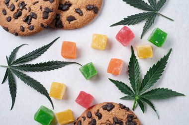 Marmelat ve esrarlı Amerikan kurabiyeleri. CBD yağlı tatlılar. Beyaz arka planda marihuana yaprakları. Üst manzara, düz uzanma.