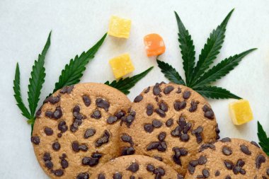 Esrar özlü Amerikan kurabiyeleri. CBD yağlı tatlılar. Beyaz arka planda marihuana yaprakları. Üst manzara, düz uzanma.