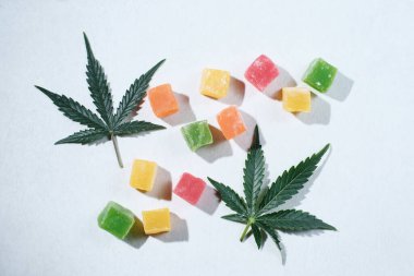 Beyaz desenli arka planda renkli marmelat ve marihuana bitkisinin düzeni