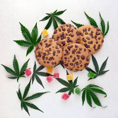 Esrar özlü Amerikan kurabiyeleri. CBD yağlı tatlılar. Beyaz arka planda marihuana yaprakları. Üst manzara, düz uzanma.