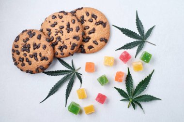 Esrar özlü Amerikan kurabiyeleri. CBD yağlı tatlılar. Beyaz arka planda marihuana yaprakları. Üst manzara, düz uzanma.