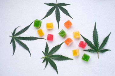 Beyaz desenli arka planda renkli marmelat ve marihuana bitkisinin düzeni