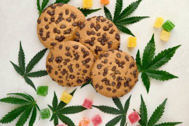 Esrar özlü Amerikan kurabiyeleri. CBD yağlı tatlılar. Beyaz arka planda marihuana yaprakları. Üst manzara, düz uzanma.
