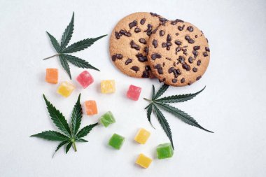 Esrar özlü Amerikan kurabiyeleri. CBD yağlı tatlılar. Beyaz arka planda marihuana yaprakları. Üst manzara, düz uzanma.