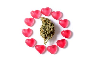 Esrar ve sevgililer günü konsepti. Beyaz izole bir arka planda kalp şeklinde şekerlemeleri olan esrar tomurcukları