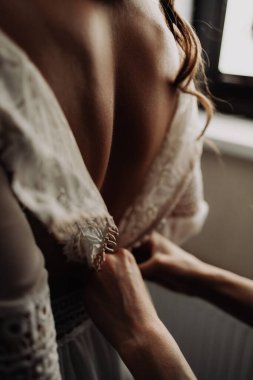 Gelinliğin düğmelerini iliklemek ve giyinmek için bir kızın sırtına yakın çekim.