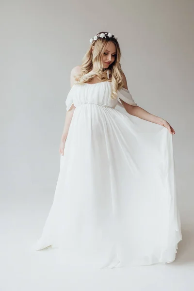 Blondynka Ciąży Białej Sukience Wieńcem Głowie Studio Białym Tle Trzyma — Zdjęcie stockowe