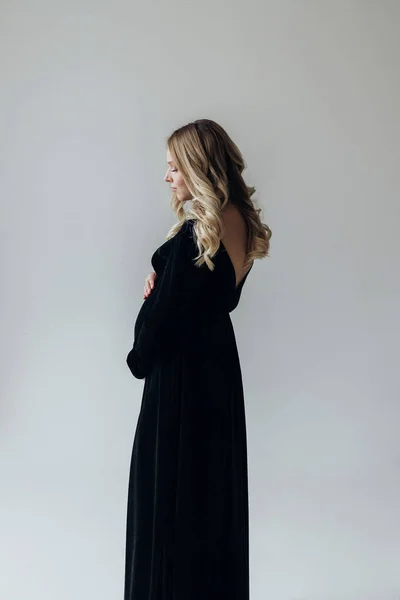 Těhotná Blondýna Žena Černých Šatech Stojí Studiu Bílém Pozadí Drží — Stock fotografie