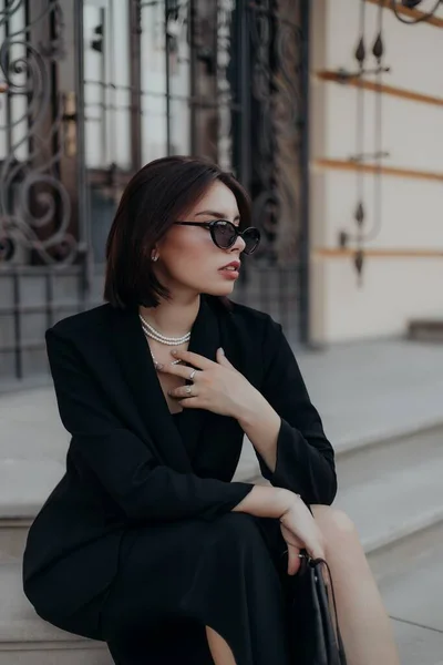 Una Chica Morena Una Chaqueta Vestido Negro Gafas Negras Sienta — Foto de Stock