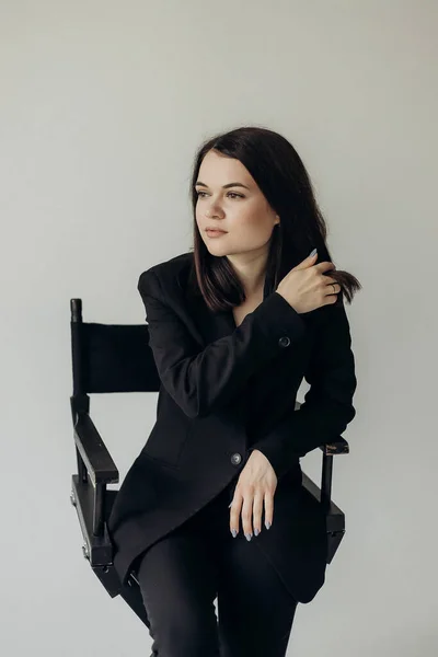Girl Black Suit White Background Sits Chair — Zdjęcie stockowe