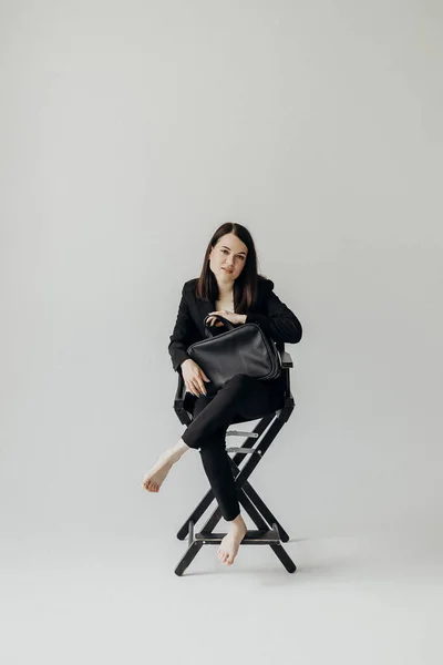 Girl Black Suit Bag White Background Sits Chair — Zdjęcie stockowe