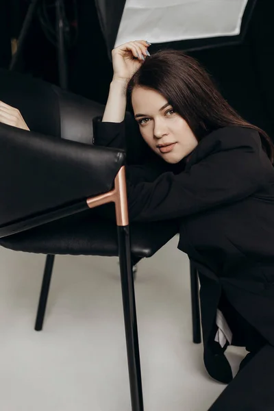 Girl Black Suit White Background Sits Floor Chair — Zdjęcie stockowe