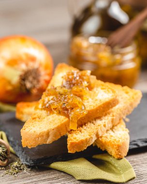 Tahta bir masada kızarmış ekmeğin üzerinde soğan ziyafeti. Ev yapımı soğan reçeli