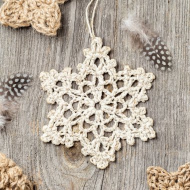 Tığ işi kar tanesi, doğal malzemelerden yapılmış el yapımı Noel süsü. Üst manzara, düz uzanma.