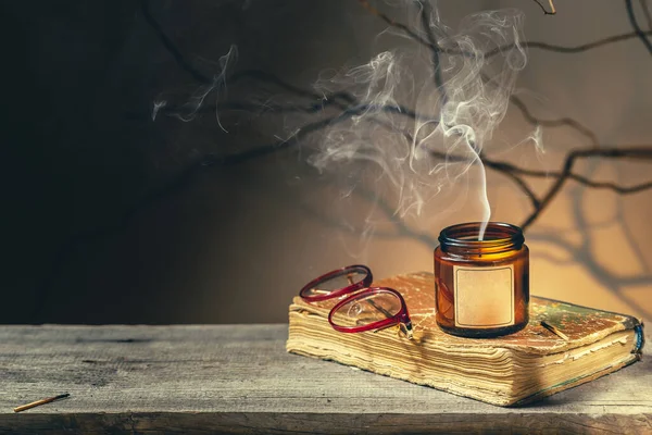 Eski bir antika kitap, gözlük ve gece sönmüş mumla donatılmış eski bir geçmiş. Ağaç brunch 'ları ve gölgeler ürkütücü karanlık akademi havası yaratır. Sıcak sonbahar okuma zamanı