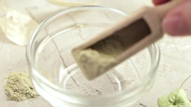 Yüz ve saç bakımı için Ayurvedic kozmetik ubtan. Kadınların elleri ubtan tozu ve sudan arındırıcı bir ürün yapıyor ve cildine krem sürüyor.