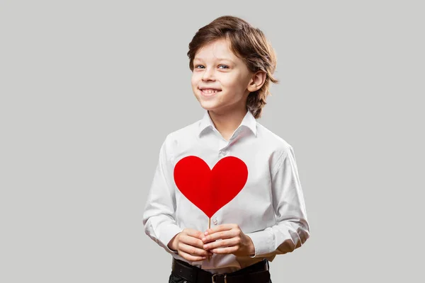 男孩抱着一颗红色情人节的心，微笑着 — 图库照片