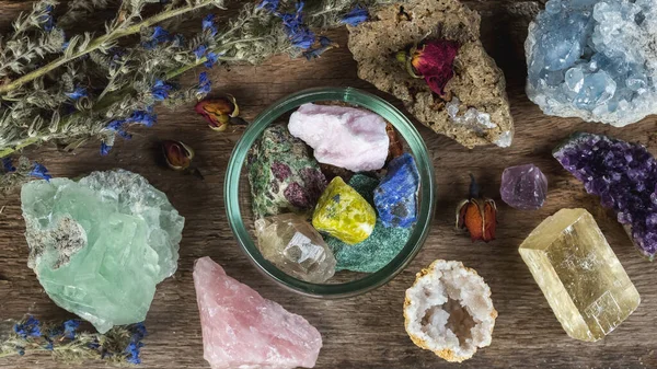 Alternative crystal healing therapy concept. Stones and minerals set up on the wooden table with dry flowers. Gemstones for esoteric spiritual practice or witchcraft