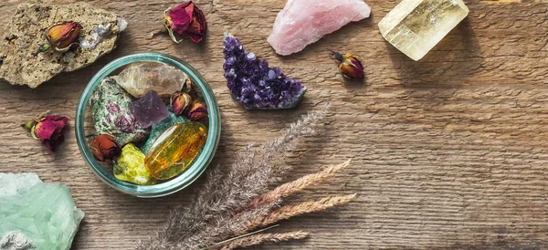 Stones and minerals collection. Alternative crystal healing concept. Gemstones for esoteric spiritual practice or witchcraft set up on wooden table with dry herbs and flowers