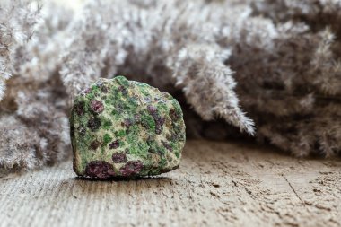Eclogite rock containing green pyroxene and red garnet or pyrope on wooden natural background with copy space clipart