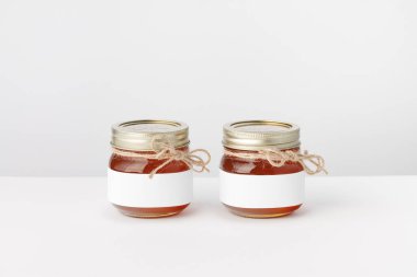 Beyaz arka planda iki kavanoz bal, ikiz ve beyaz etiket