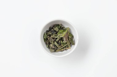 Beyaz bir kasede kuru çay yaprakları.