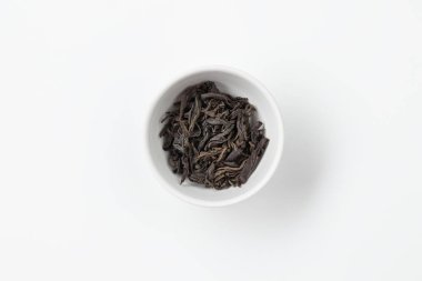 Beyaz bir kasede kuru çay yaprakları.