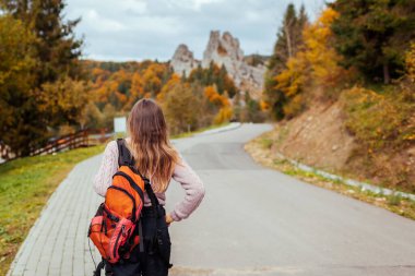 Sırt çantalı bir kadın gezgin, sonbahar Karpatya dağlarında Tustan 'da kayalara doğru yürüyor. Ukrayna 'da turizm