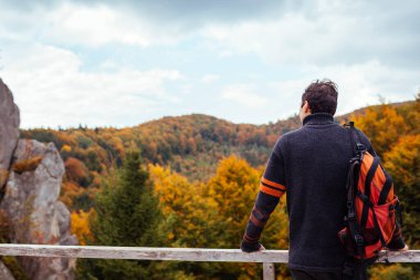 Sırt çantalı gezgin, sonbahar Karpatya dağlarında Tustan 'da kayaların yanında duruyor. Sonbaharda Ukrayna 'da turizm. Yürüyüş ve dinlenme