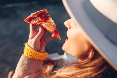 Park 'ta pizza yiyen bir kadın. Lezzetli dilimleri yakından çek. Atıştırmalık yemek.