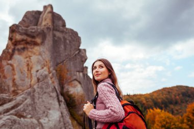 Sırt çantalı kadın gezgin sonbahar Karpatya dağlarında ormanda kayaların arasında yürüyor. Ukrayna 'da sonbahar turizmi. Yürüyüş ve dinlenme