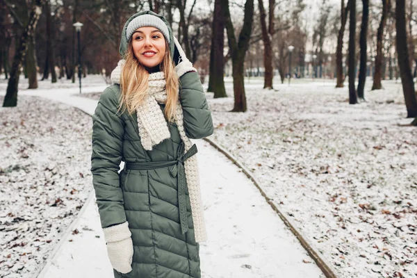 冬季时尚 在雪地的公园里 年轻的女人穿着长长的绿色外套 戴着围巾 现代服装 — 图库照片
