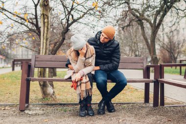 Sevgili koca, karısını destekliyor sonbahar parkında açık havada sarılıyor. Üzgün depresif kadın, ağlayarak yüzünü kapatıyor. Taşıyıcı adam acıya yardımcı oluyor.