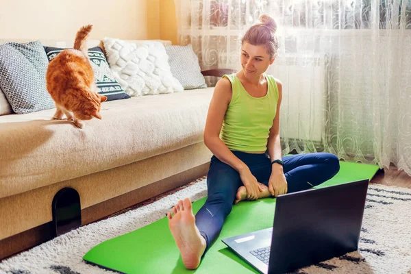 Ćwiczenia w domu podczas blokady coronavirus covid. szkolenie kobiet online za pomocą laptopa z kotem. — Zdjęcie stockowe