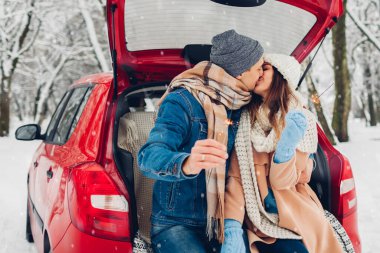 Birbirine aşık genç bir çift, karlı kış ormanlarında arabanın bagajında maytap yakıyor. İnsanlar Noel tatili boyunca dışarıda dinleniyorlar.